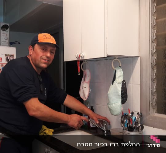 אדם מתקן ברז במטבח עם כלים